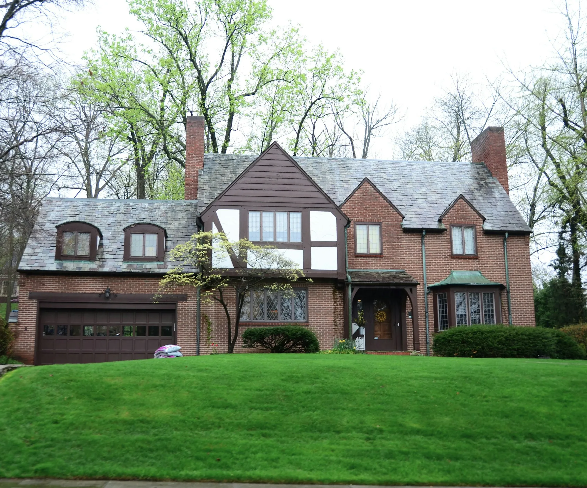 Tudor-style brick home with an attached garage and green lawn
