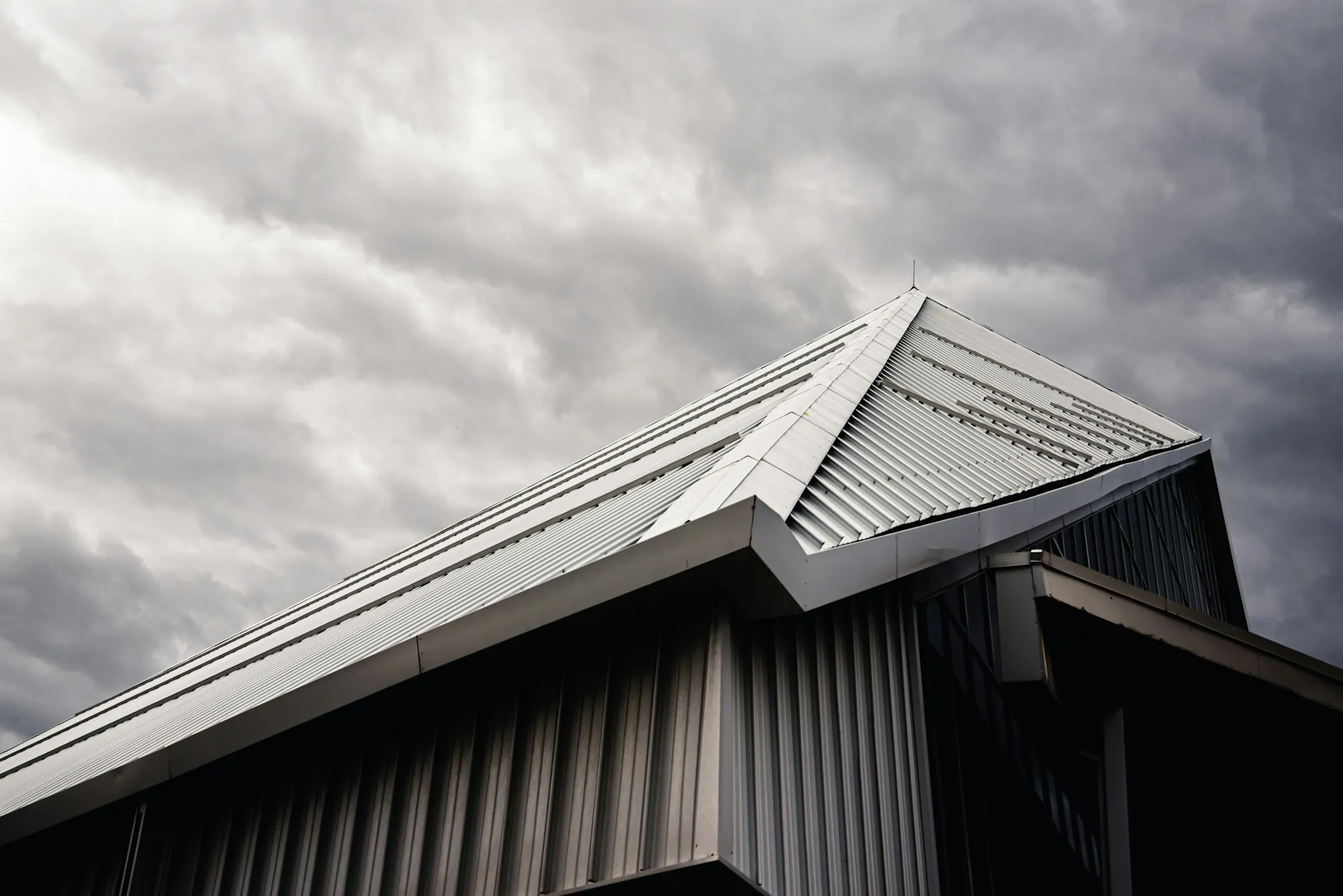 Silver metal roof edge under a dramatic cloudy sky